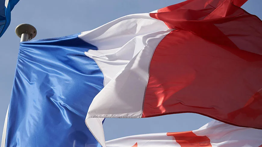 French national flag with blue, white, and red vertical stripes waving in the wind.